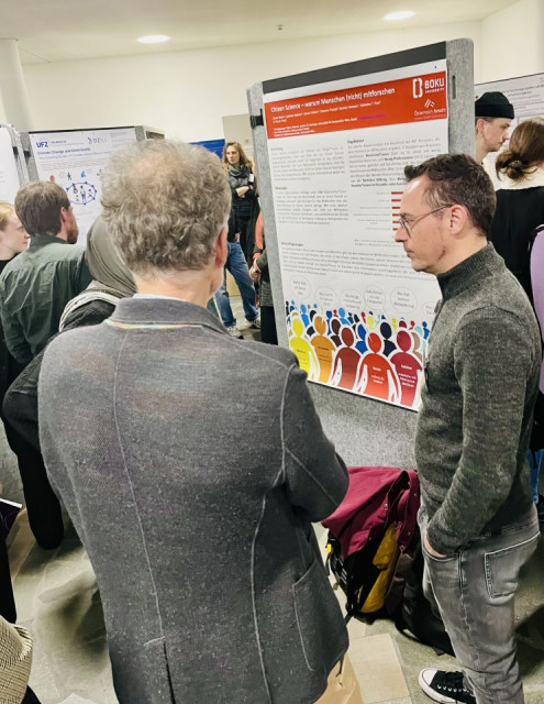 Vielen Menschen stehen vor einem Plakat.