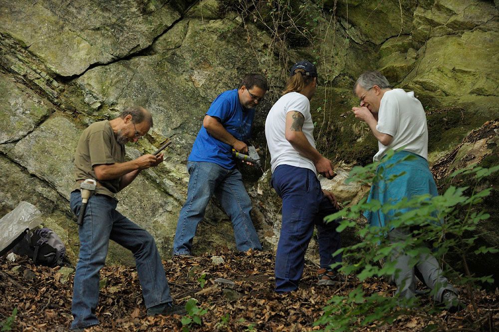 Vier Personen vor großem Felsen mit Werkzeug